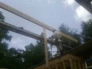 Carpenter setting a ridge beam over a new addition frame — Ice Dam Removal by Roofing Brothers in Neihart