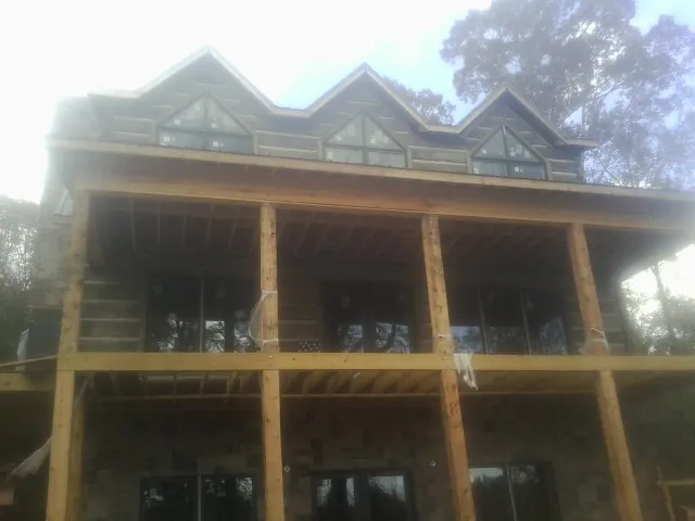 Dormers and porch framing on a large log home under construction — Roof Coating work by our crew in Neihart
