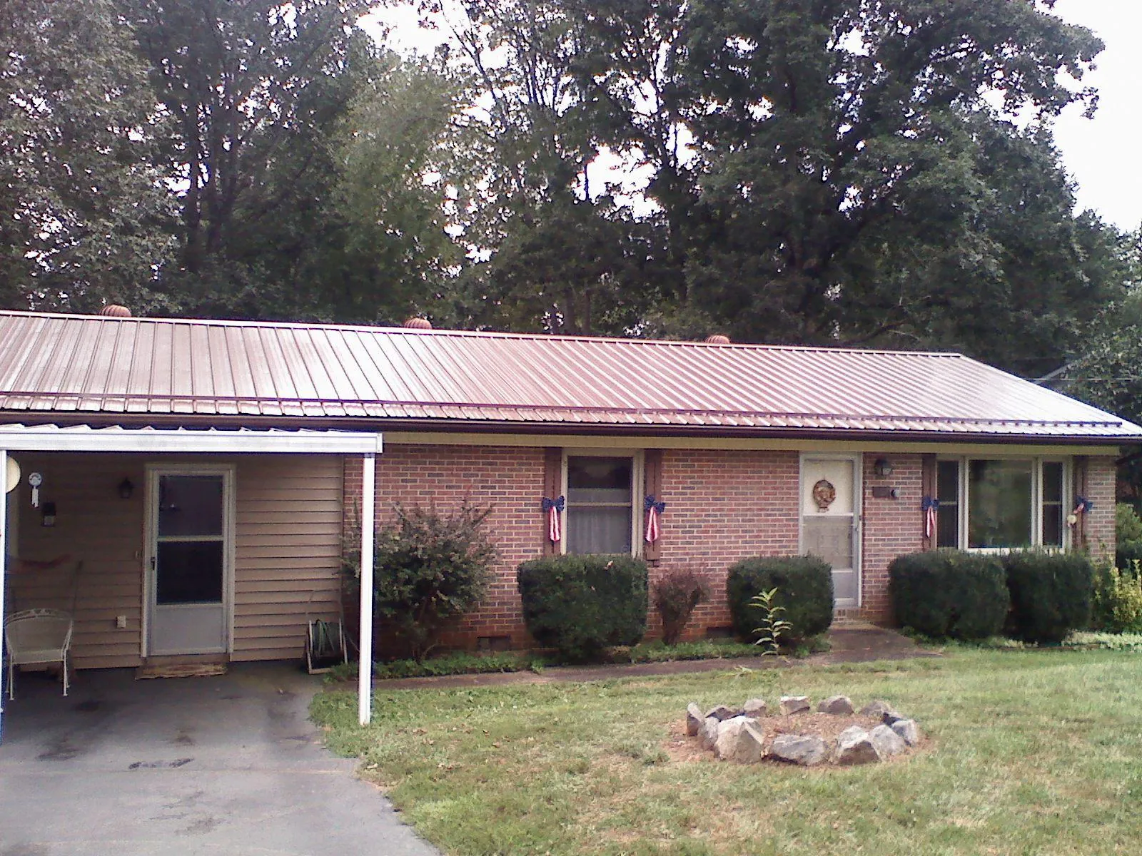 Bronze metal roof and carport on a brick ranch home — Roof Repair work by our crew in Neihart
