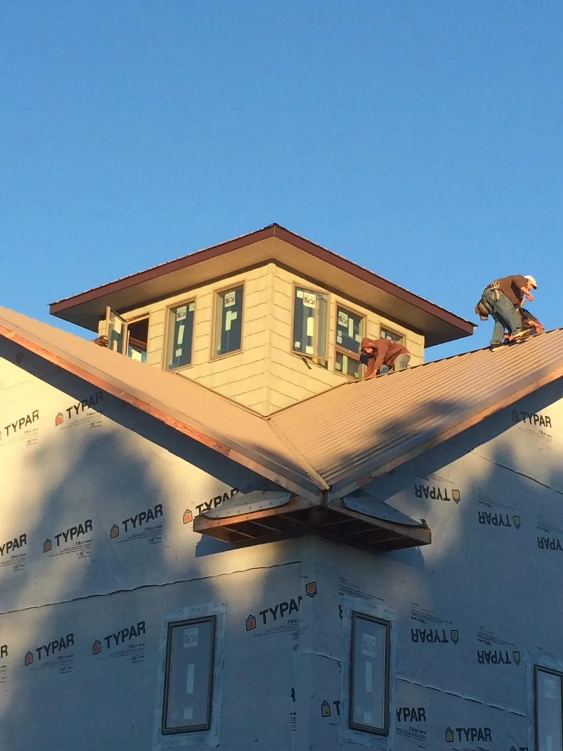 Roofers working around a rooftop cupola on a new metal roof at sunset — Roof Waterproofing in Neihart by Roofing Brothers